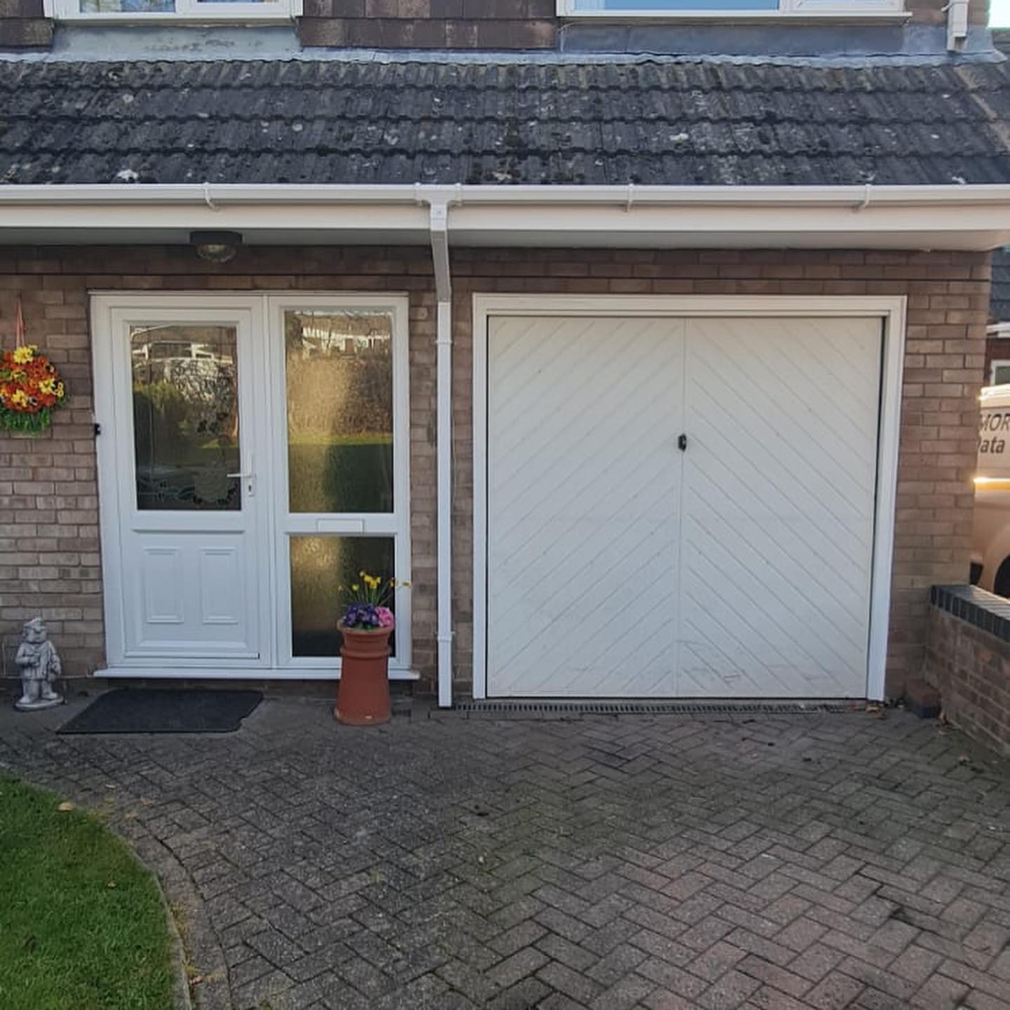 White garage door with a chevron pattern beside a white front door