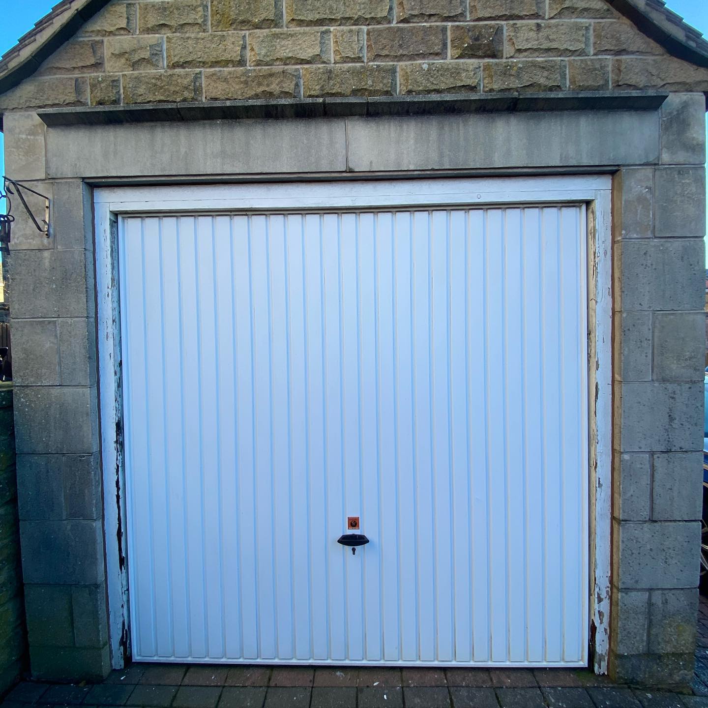 White ribbed garage door set in a stone frame